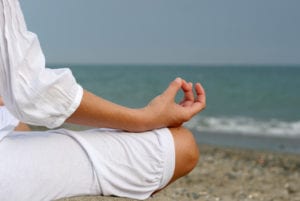 A woman is meditating by the sea